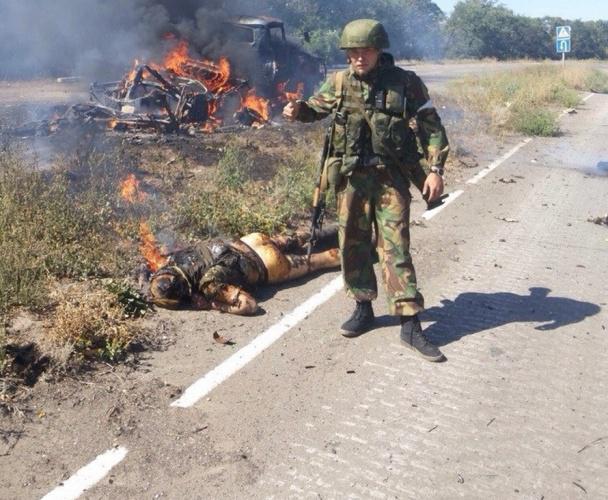 Forces spéciales de la Fédération de Russie est photographié sur fond de corps mutilés et des soldats ukrainiens piétinés sur le drapeau ukrainien. histoire de l'image Спецназ РФ фотографируется на фоне искалеченных тел украинских воинов и топчется по украинскому флагу. ФОТОрепортаж